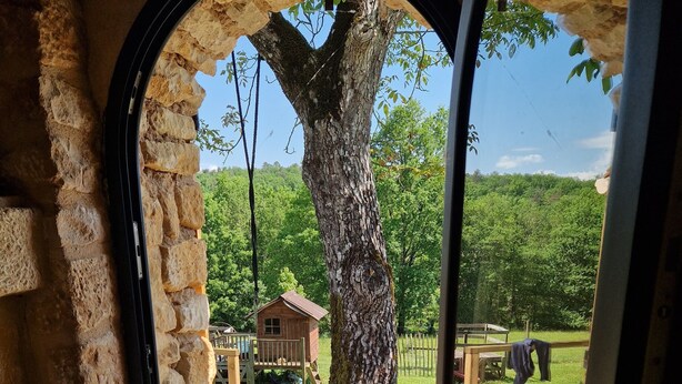 Un arco de entrada da a un espacio empedrado con una terraza de madera y una pequeña construcción de madera.