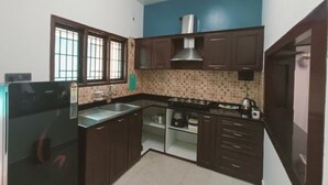 Una cocina con armarios de madera oscura, un extractor de acero inoxidable, un microondas y un lavamanos.