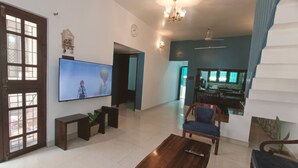 Una sala de estar con televisor, muebles de madera, una escalera y un comedor.