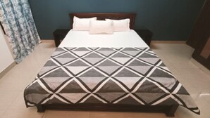 Una cama con una colcha de estampado geométrico, un cabecero de madera y una pared lisa.