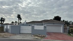 A residential house with a gated driveway, a garage, and a paved walkway. - Cosy space for work or getaway close to Blougberg beach Cape Town (Cape Town)