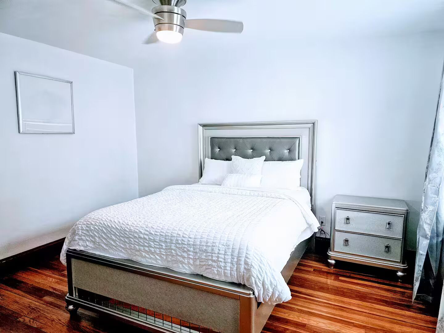 A neatly arranged bedroom with a bed, bedside tables, and a ceiling fan.