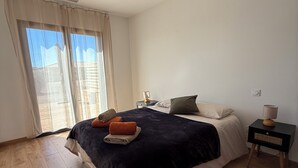 A bedroom with a large bed, a bedside table, a lamp, and a window with curtains. - Air-conditioned house, South Corsica, 4 bedrooms, 2 bathrooms, 15 min from the beach (Figari)