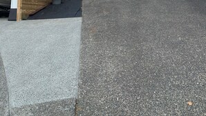 Una casa moderna de dos pisos amb garatge, terrassa de fusta i una planta en test.