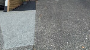 Een modern huis met twee verdiepingen, een garage, een houten terras en een plant in een pot.