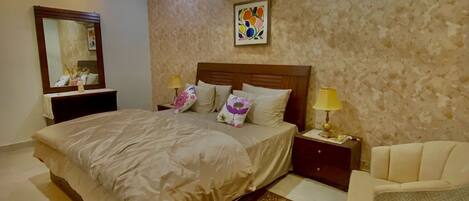 A bedroom with a bed, bedside tables, a chair, a mirror, and a ceiling fan.