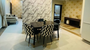 A modern dining area with a marble accent wall, black and white patterned chairs, and a glass table.
