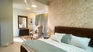 A modern bedroom with a large bed, a nightstand, a dresser, and a mirror.