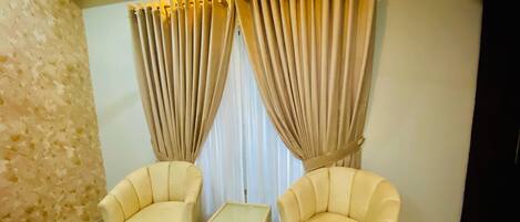 A room with two armchairs, a small table, and a patterned rug.