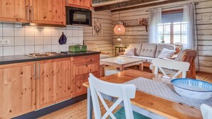 Une cuisine chaleureuse, aménagée dans le style d’un chalet, avec des meubles en bois, un four à micro-ondes et un coin repas comprenant une table et des chaises.