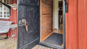 Une porte en bois avec un trou de serrure, un banc et une pancarte indiquant « Bienvenue ».