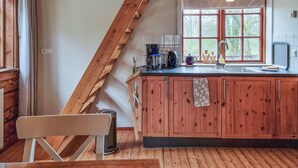 Une cuisine avec des meubles de rangement en bois, une grande fenêtre et un escalier en bois.