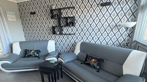 Una sala moderna con un sofá seccional gris, una pequeña mesa de centro negra y una pared con estampado.