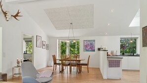 Un grand espace de vie comprenant un coin repas avec une table, un canapé et une cuisine avec une fenêtre.