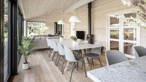 A modern dining area with a long table, chairs, pendant lights, and a fireplace. - "Faidra" - 1.1km from the sea by Interhome (Hirtshals)