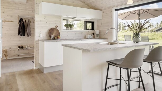 A modern kitchen with a large island, white cabinetry, and a window overlooking a garden. - "Faidra" - 1.1km from the sea by Interhome (Hirtshals)