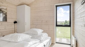 A bedroom with a bed, a white wardrobe, and a large window with a view of the outdoors. - "Faidra" - 1.1km from the sea by Interhome (Hirtshals)