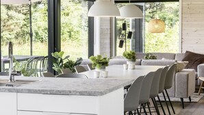 A modern kitchen with a central island, large windows, and a dining area with chairs and a sofa. - "Faidra" - 1.1km from the sea by Interhome (Hirtshals)