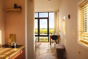 A kitchen with a large window, a dining area with a table and chairs, and a small stool. - Pean-buiten Weidum (Weidum)