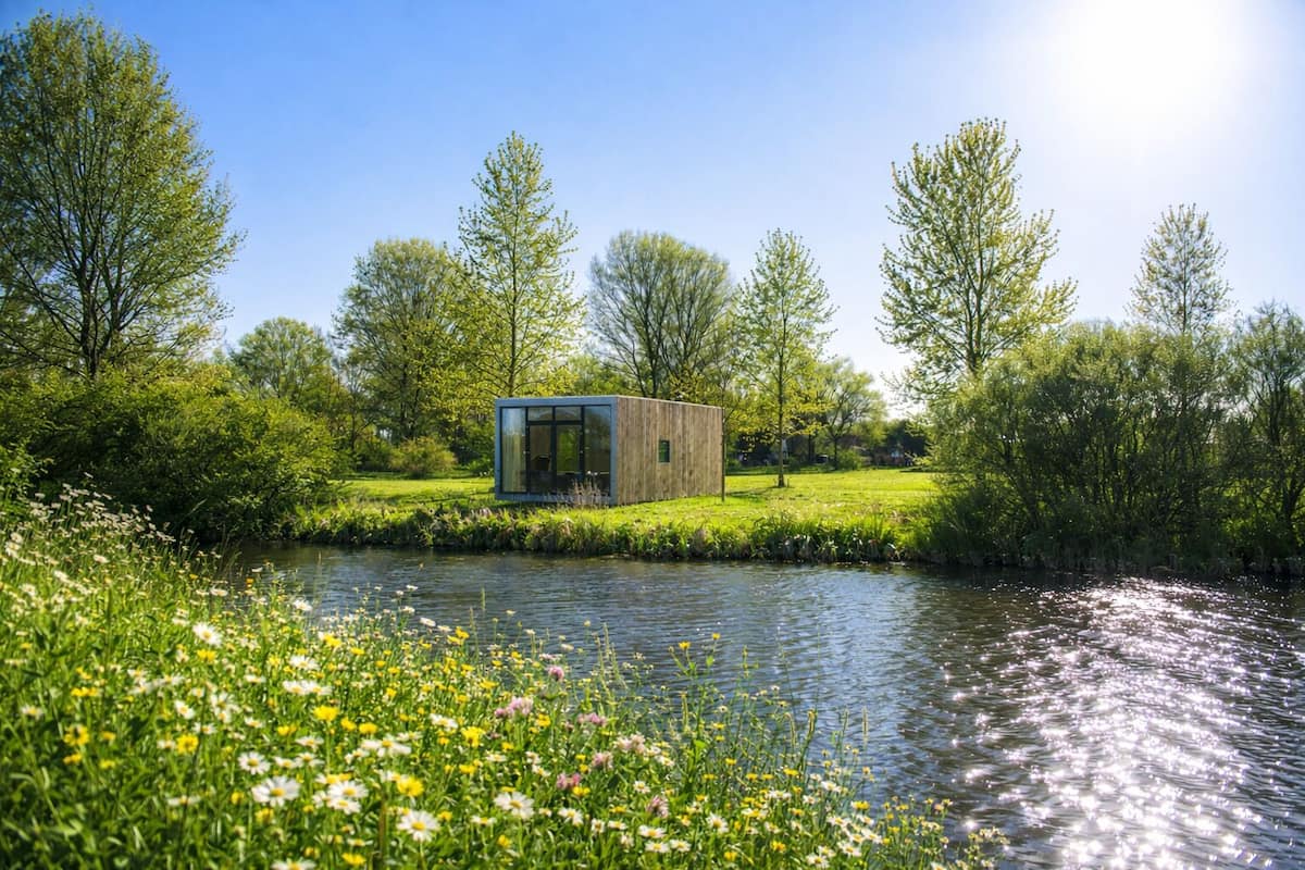 Eine moderne Glasarchitektur an einem Fluss, umgeben von üppigem Grün und Blumen.