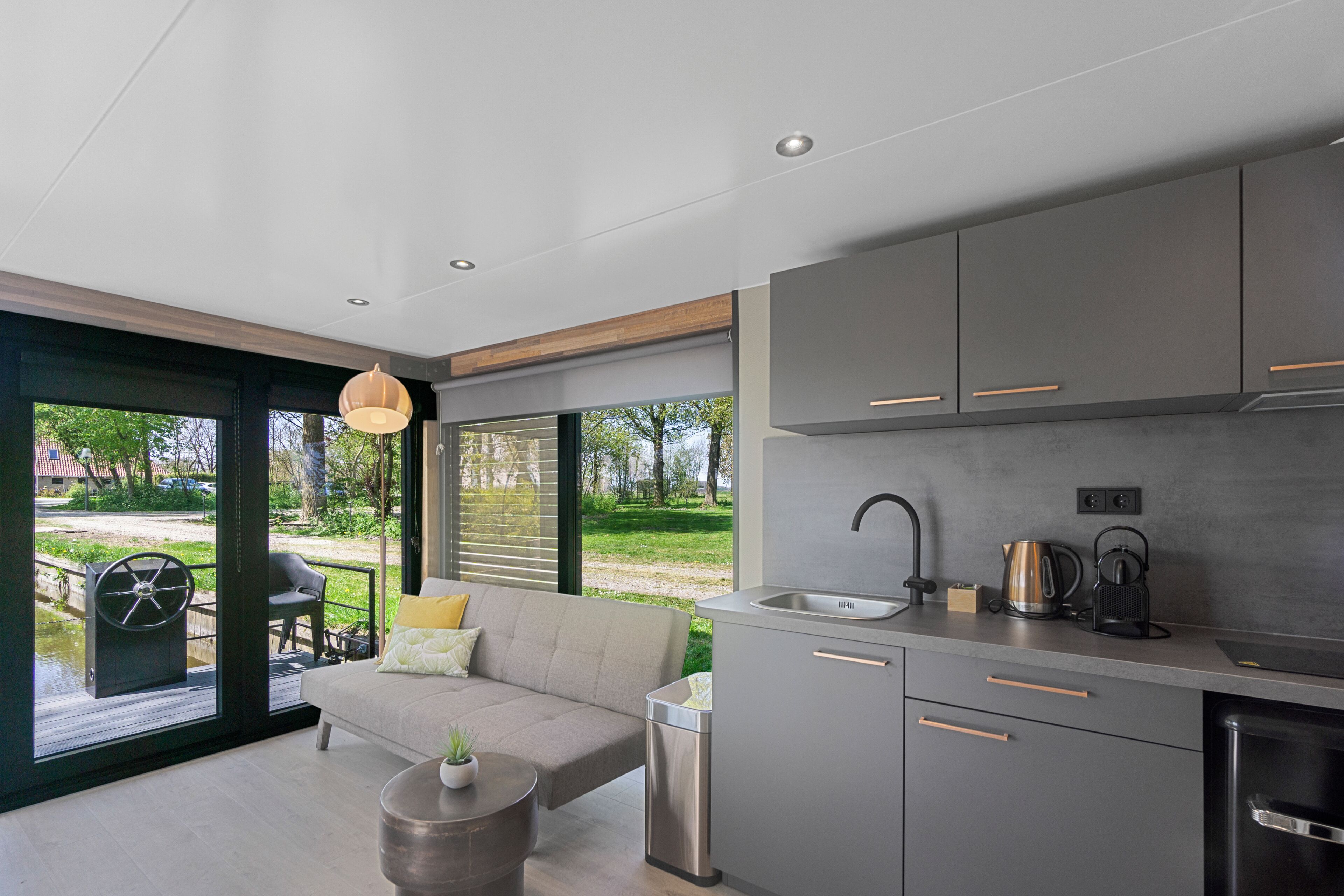 A modern kitchen with grey cabinets, a stainless steel sink, and a coffee maker.