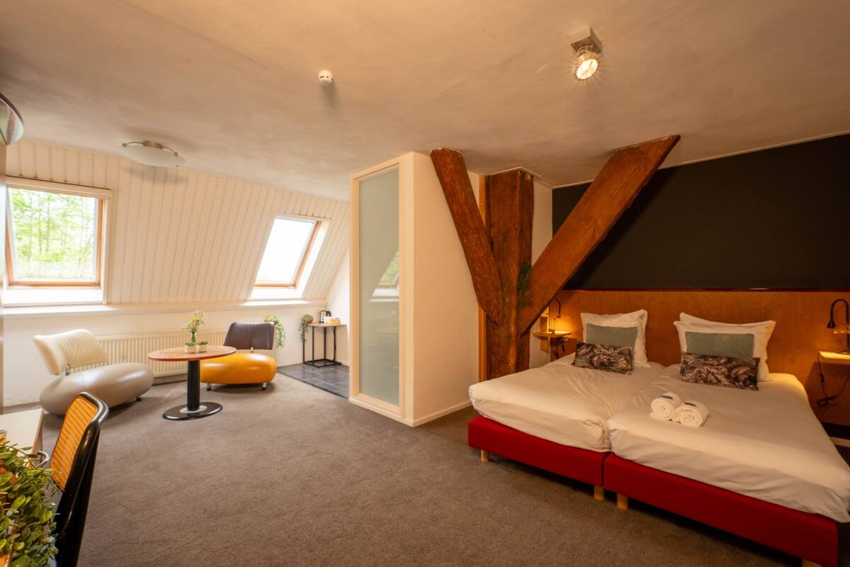 Ein modernes Hotelzimmer mit einem großen Bett, einer kleinen Sitzecke und Blick ins Freie.