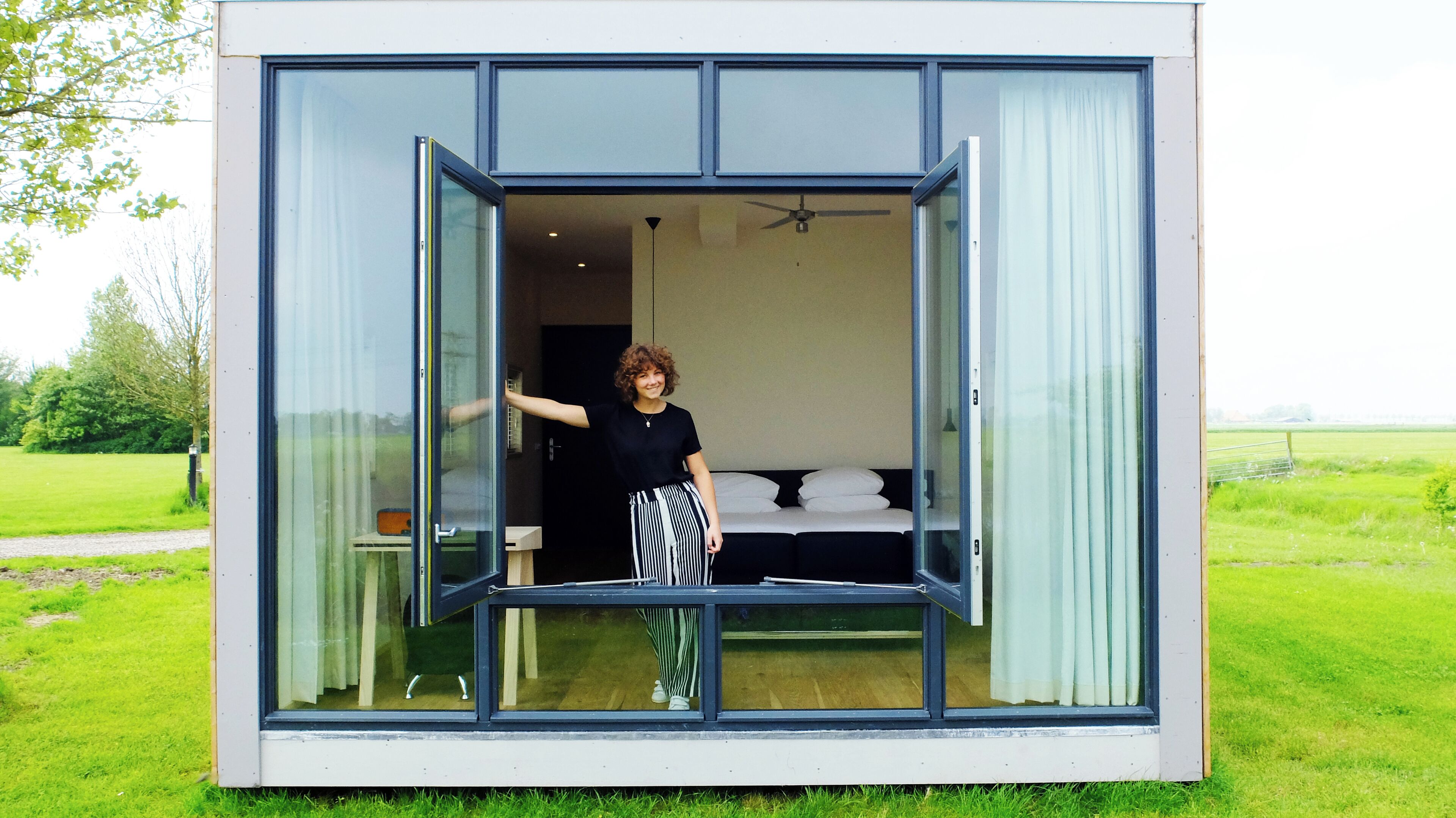 Una habitación moderna y compacta con una cama, una mesita y una silla.