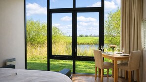 A bedroom with a large window, a bed, and a dining area with chairs and a table. - Pean-buiten Weidum (Weidum)