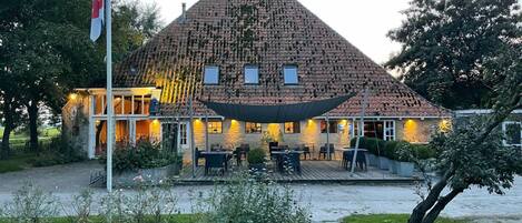 A building with a tiled roof, a flagpole, and outdoor seating.
