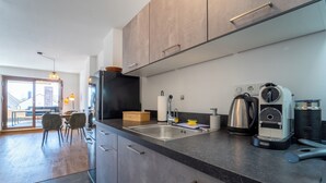 A modern kitchen with dark cabinets, a stainless steel sink, and a coffee machine.