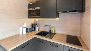 Ett modernt kök med en inbyggd ugn, en diskho och en diskmaskin.
