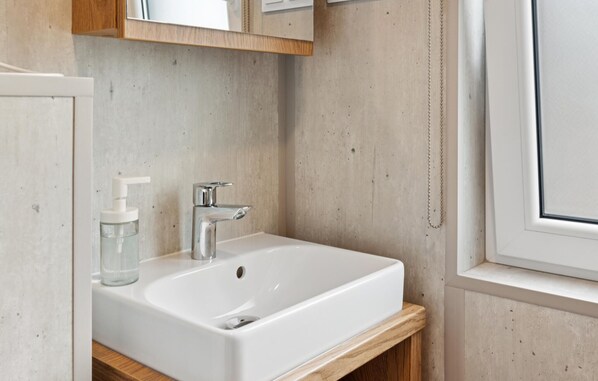 A bathroom with a white sink, a chrome faucet, and a wooden vanity. - Gorgeous home in Erkheim with WiFi (Erkheim)