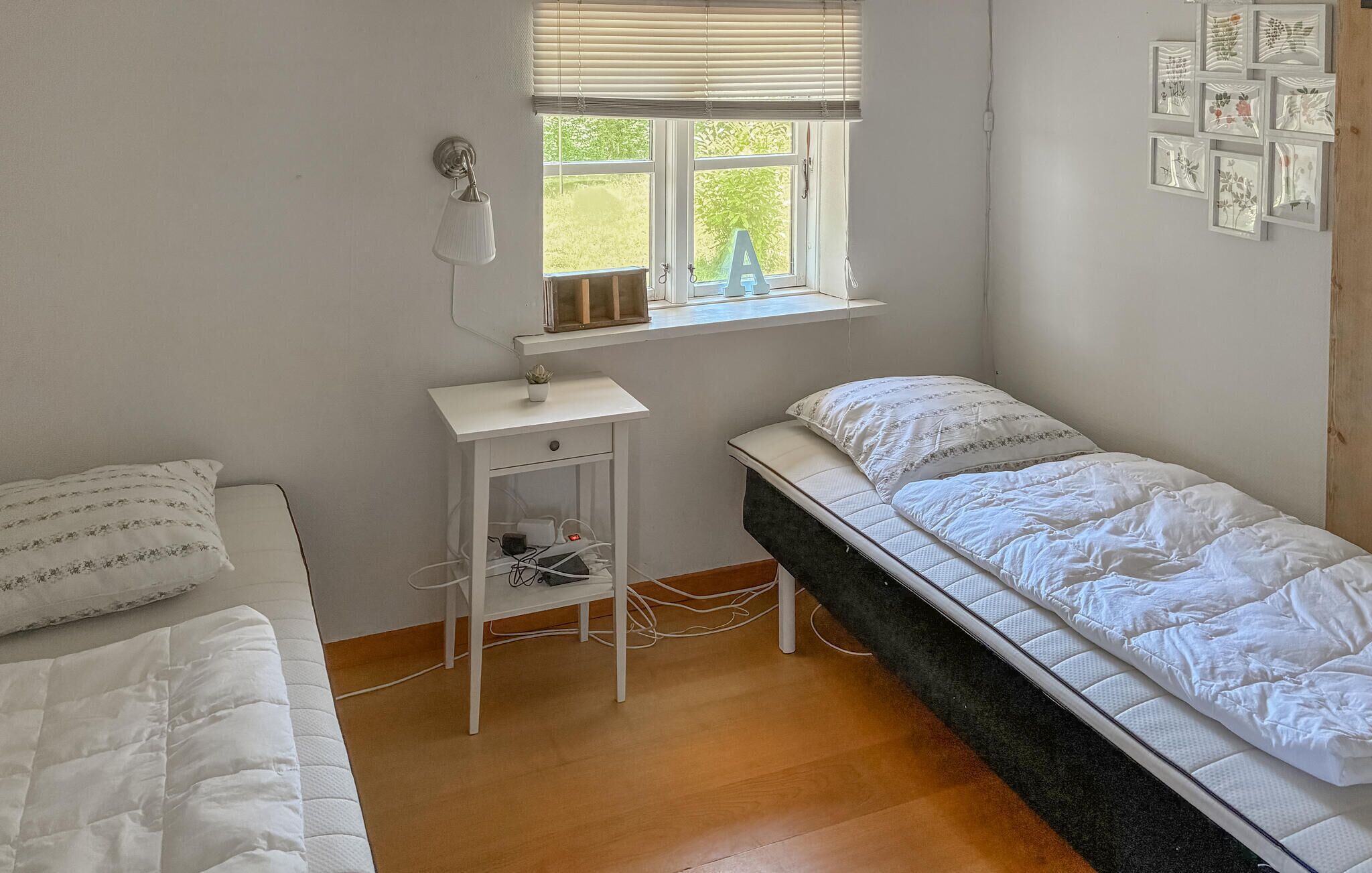 Un dormitorio con dos camas, un escritorio, una ventana con persianas e imágenes enmarcadas en la pared.