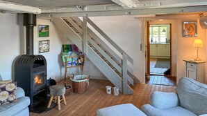 Una sala de estar acogedora con una estufa de leña, una escalera y vistas a la cocina.