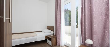 Un dormitorio con cama, mesita de noche y escritorio con lámpara.