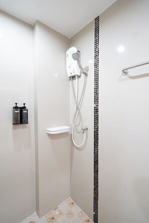 Une salle de bain moderne équipée d’une douche, de toilettes et de deux distributeurs de savon.