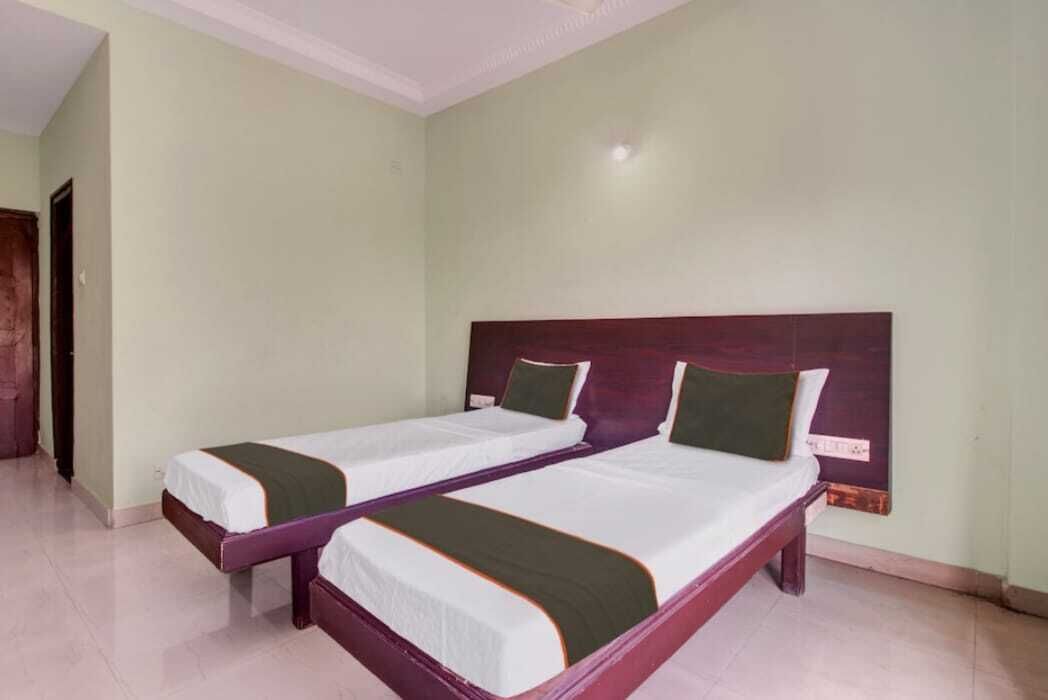 A room with two single beds, each with a wooden headboard and green bedding.
