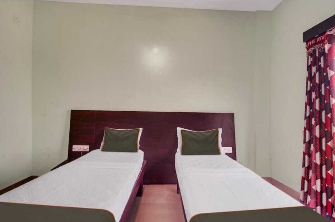 Una habitación con dos camas individuales, cada una con cabecero de madera y almohadas verdes.