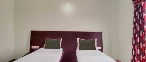 Una habitación con dos camas individuales, cada una con cabecero de madera y almohadas verdes.