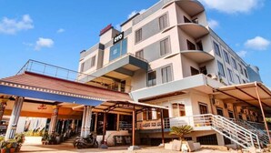 Un hotel de varios pisos con un diseño moderno, con balcones y una zona de entrada cubierta.