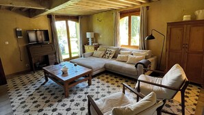 Ein gemütliches Wohnzimmer mit einer Couch, Sesseln, einem Couchtisch und einem Fernseher.