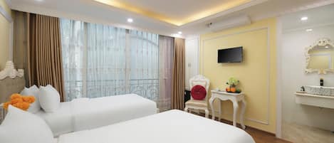 A hotel room with two beds, a television, a small table with a plant, and a mirror on the wall.