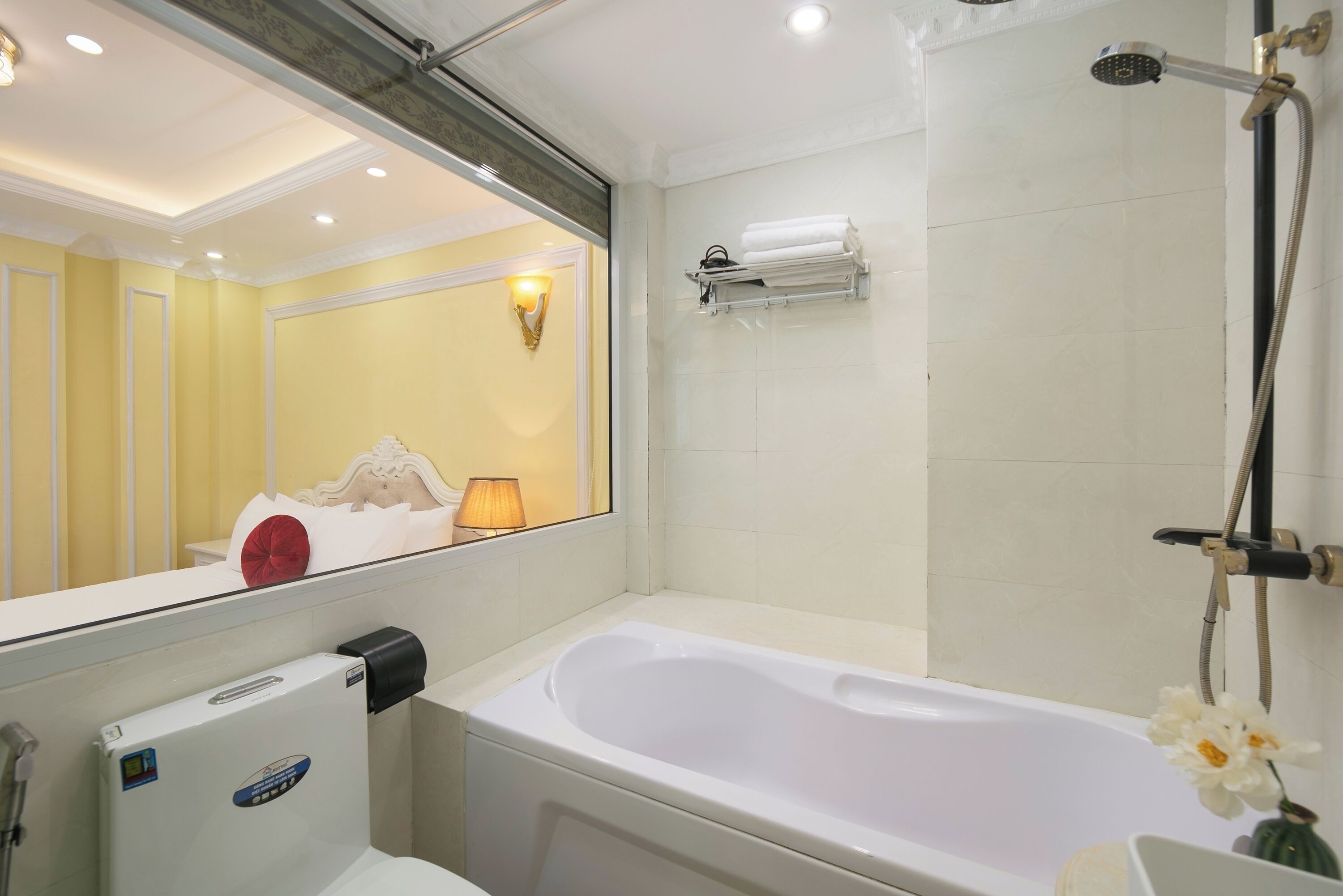 Een badkamer met een bad, douchefaucet, handdoekhouder en toilet.