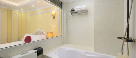 A bathroom with a bathtub, a showerhead, a towel rack, and a toilet.