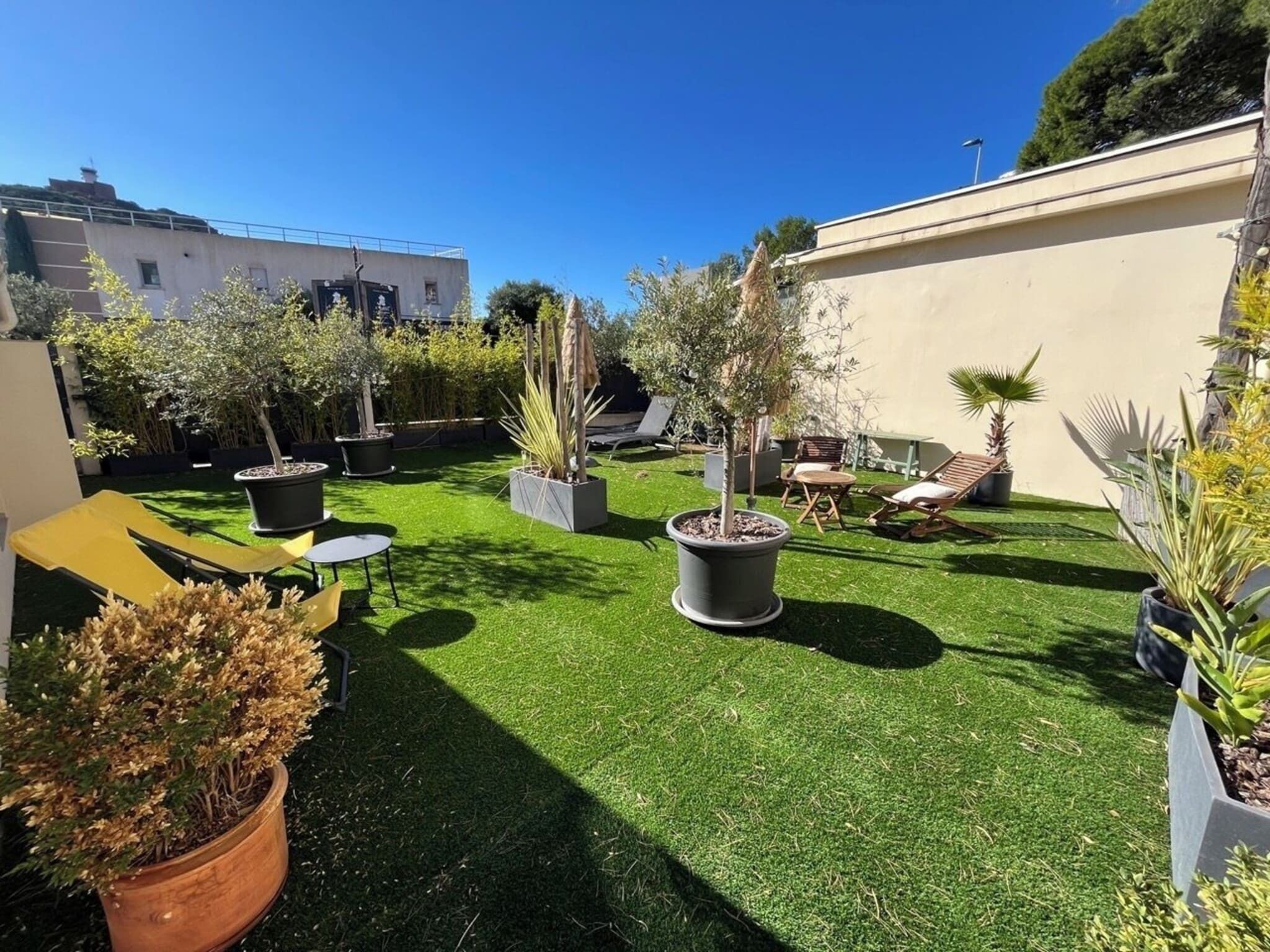 A well-maintained outdoor area with artificial grass, potted plants, and outdoor furniture.