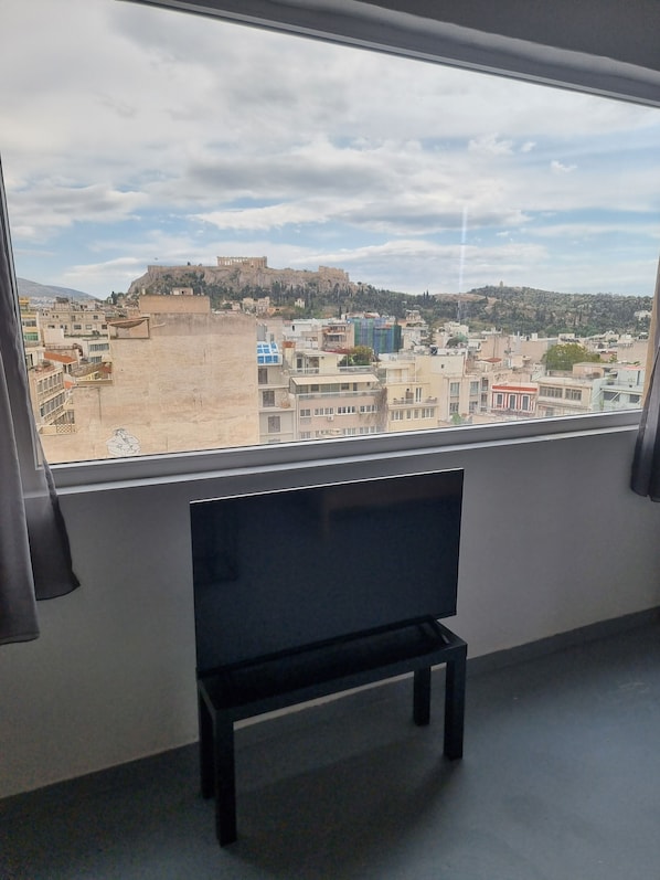 Una habitación con un amplio ventanal que da a una vista panorámica de la ciudad, incluyendo una colina con una estructura similar a una fortaleza.