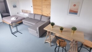 A modern room with a grey sofa, a wooden dining table with chairs, a glass coffee table, and a wooden partition wall. - athens parthenon view (Athens)