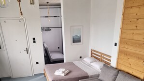 A modern bedroom with a bed, a grey sofa, a small table, and a wooden wardrobe. - athens parthenon view (Athens)