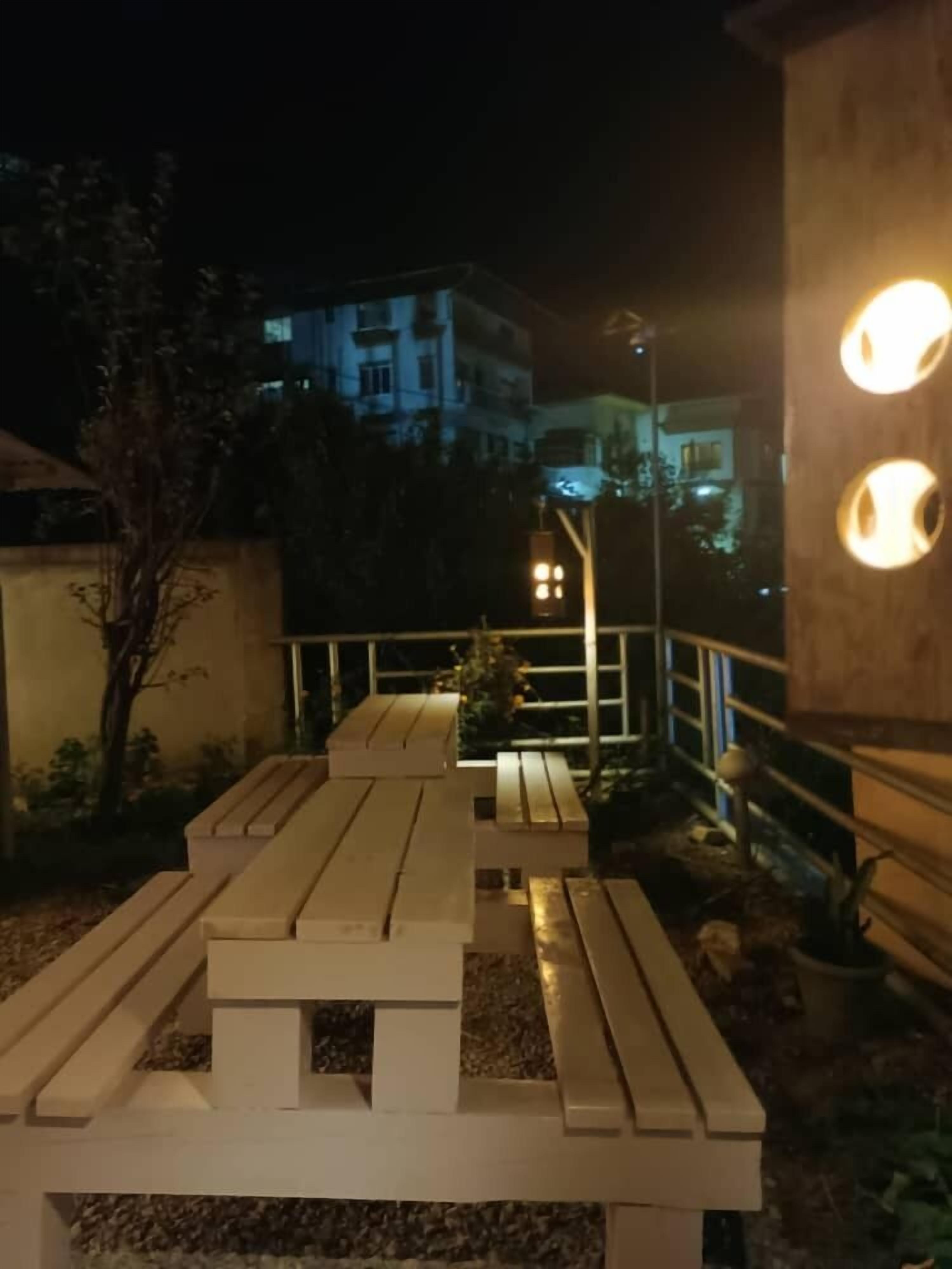 A nighttime outdoor seating area with wooden benches and a railing.