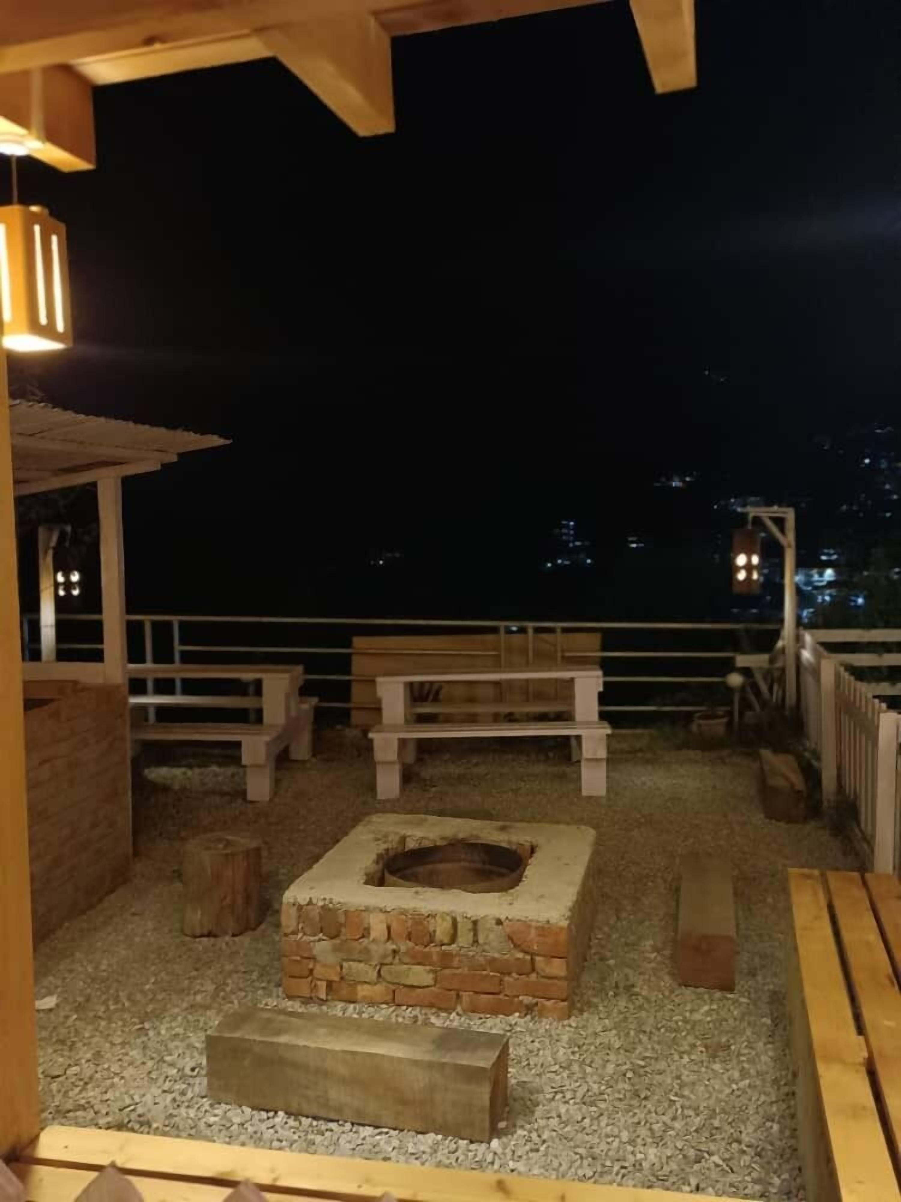Un patio al aire libre con una chimenea, bancos y una pérgola de madera.